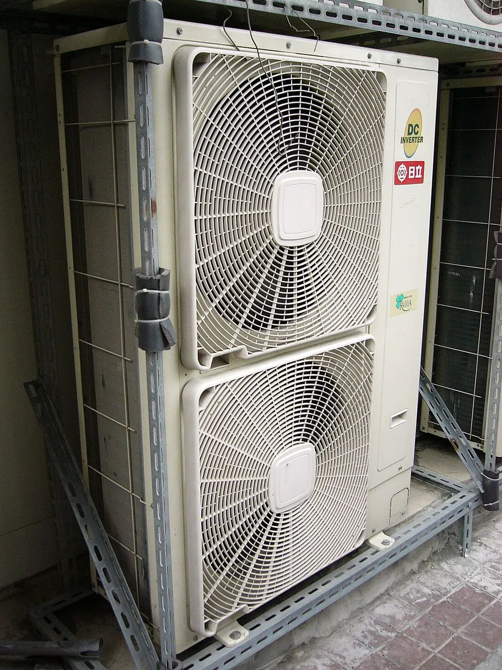 兩台分離式冷氣室外機並排緊貼牆面安裝，出風面朝外，彼此距離很近。
